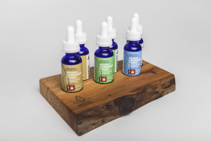 Bottles of cannabis tonic displayed on a piece of wood.