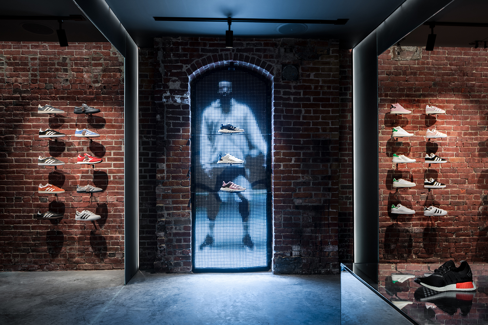 A LED curtain depicting a low resolution, half-tone image of a basketball player, set in an alcove in a brick wall that doubles as a shoe display.