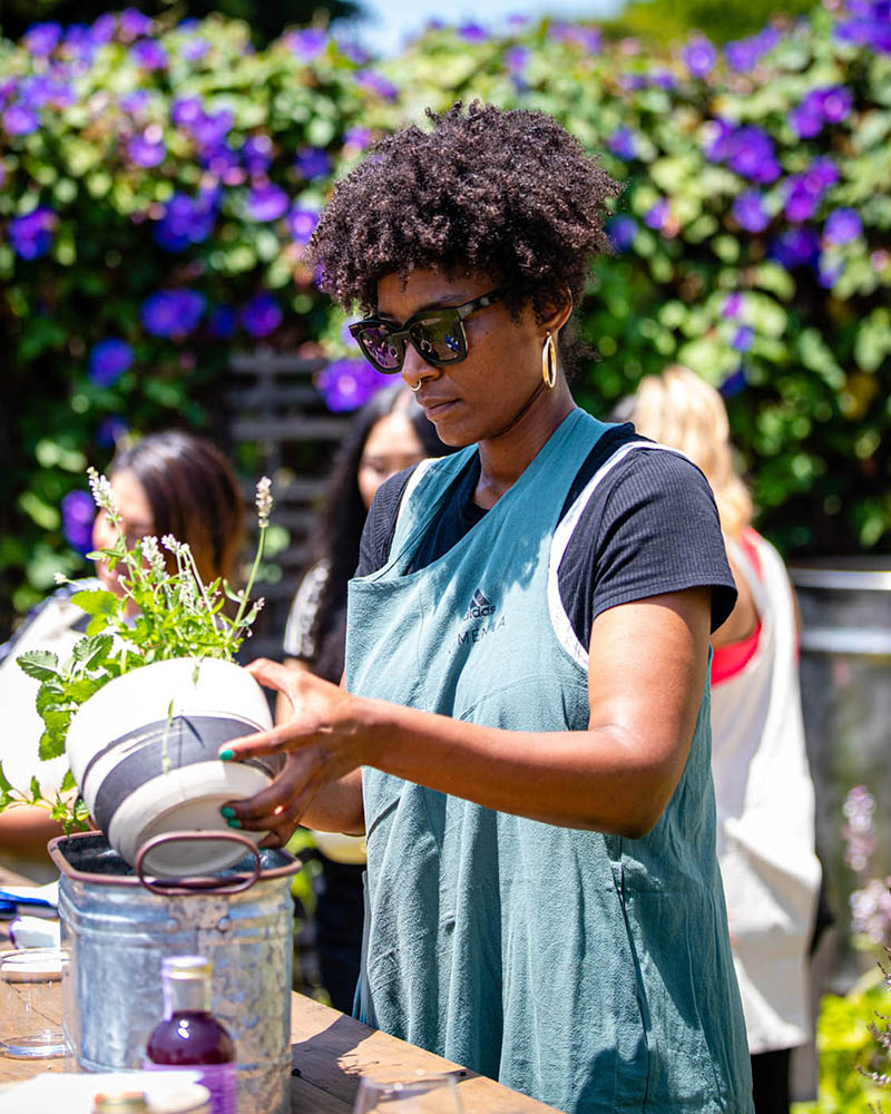 A woman plants an herb in a pot at an adidas Women’s event.