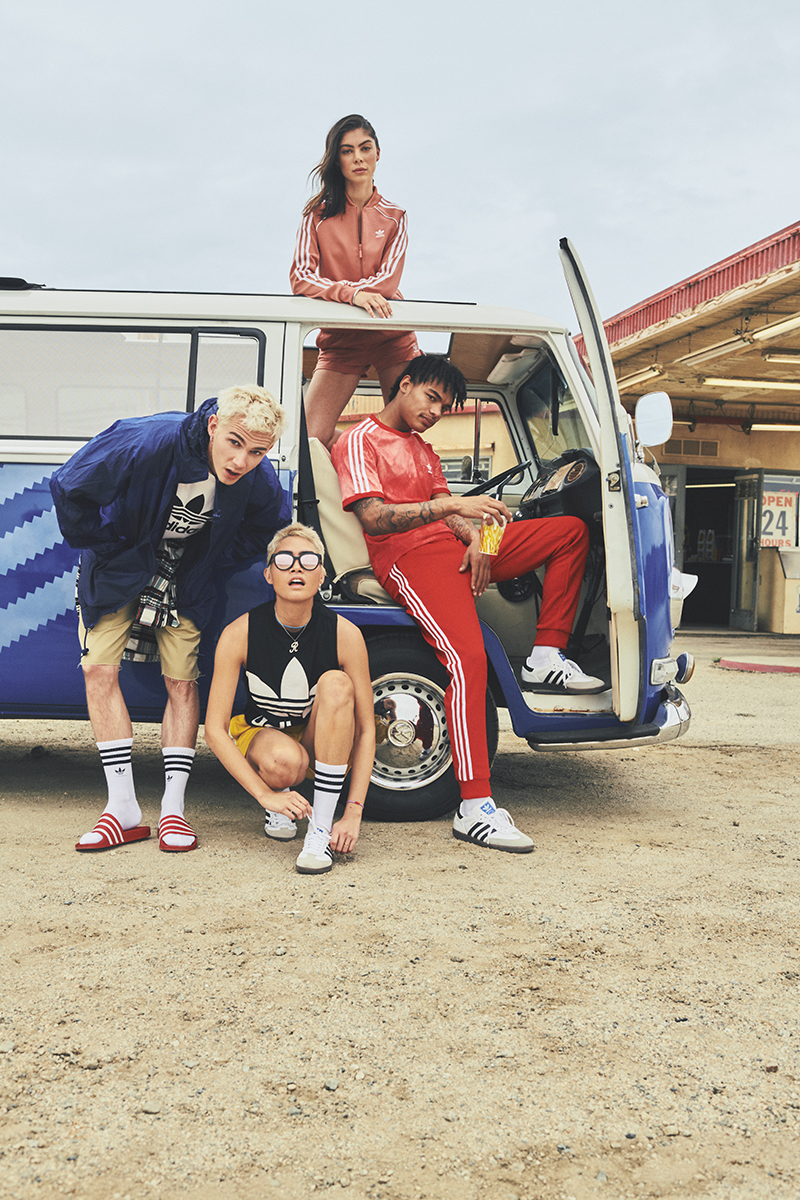 A group of four people, decked out in adidas gear, pose in and around the adidas Originals VW bus.