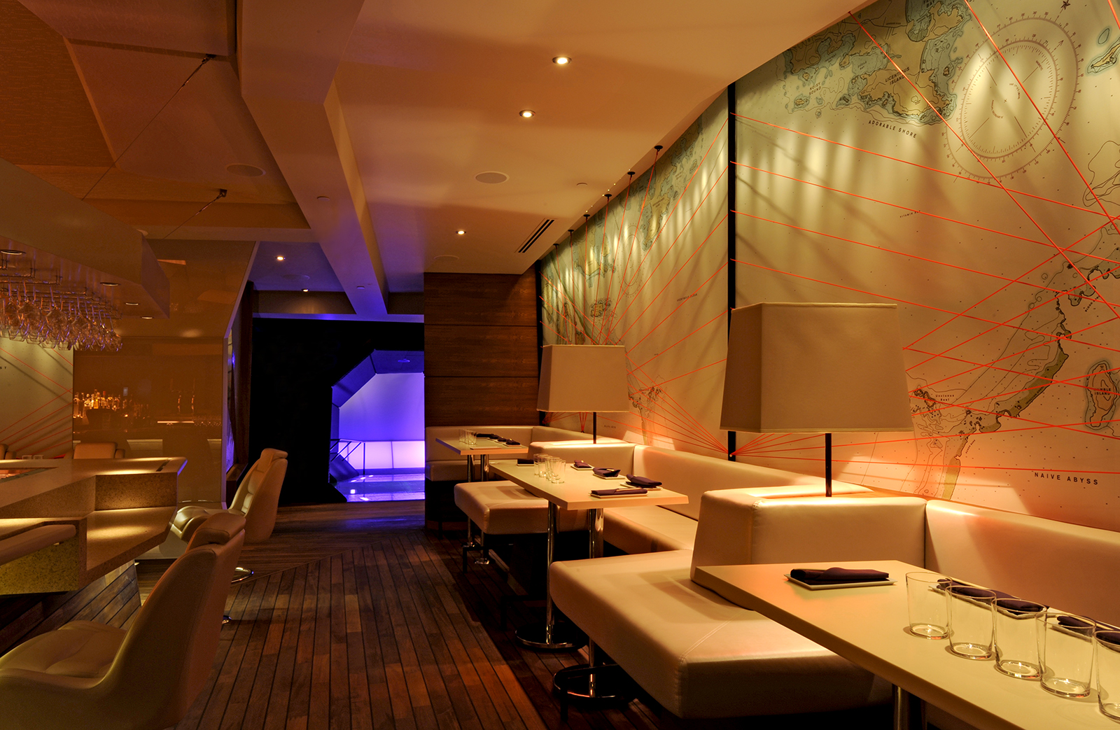The dining room with light-colored leather booths, dark wood, and the fanciful nautical maps filling the walls.
