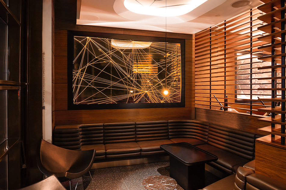 Illuminated flight paths over a dark panel on a wall above a leather and wood booth.