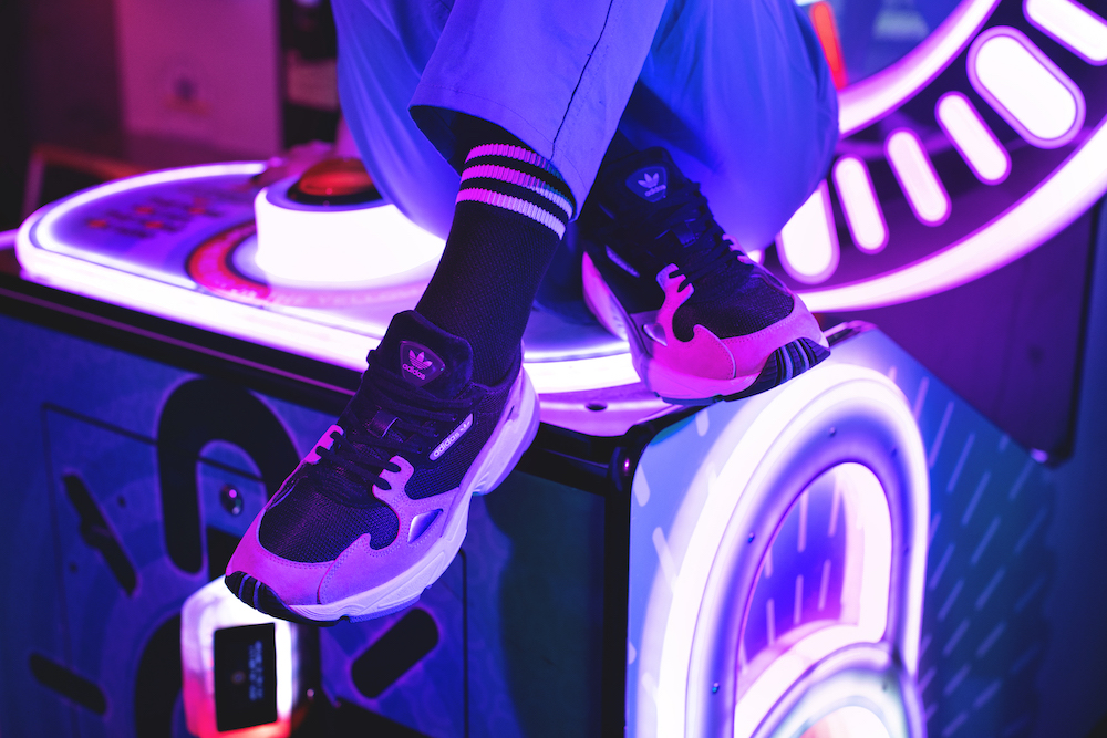 Closeup of shoes on cross-legged model seated on top of an arcade game.