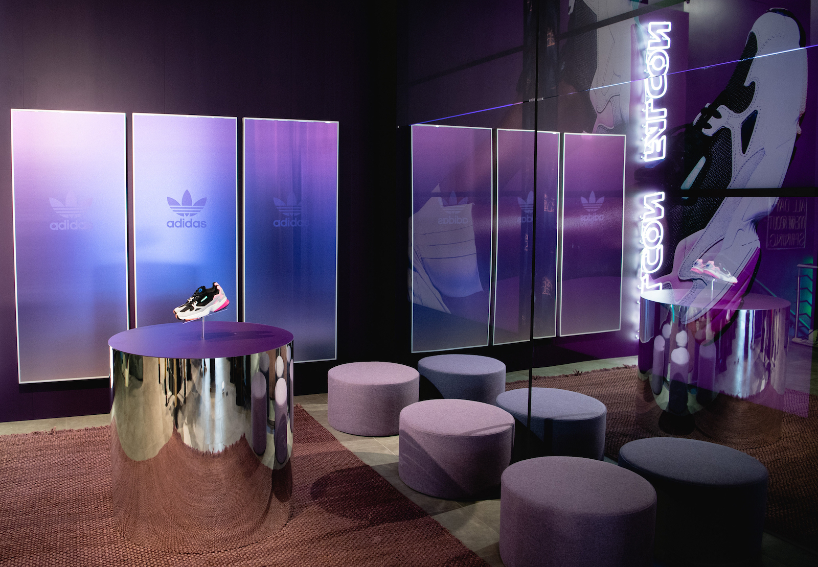 A  retail buildout with purple fogged glass, Falcon in neon, with shoes popped off a reflective cylinder pedestal.