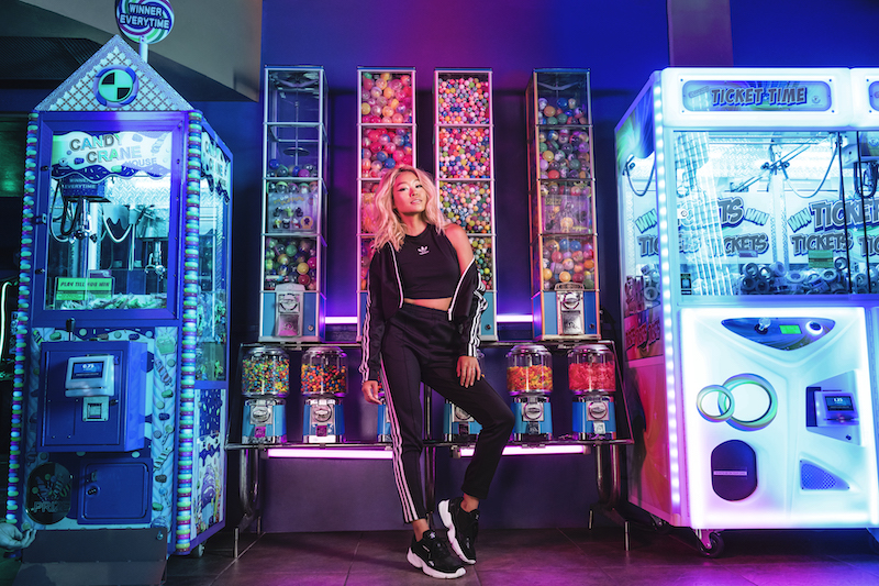 A model stands in front of a row of candy and toy vending machines.