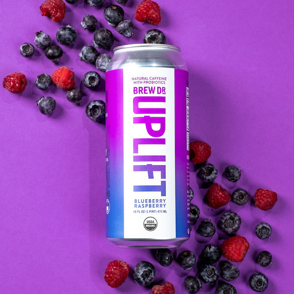 The Blueberry Raspberry Uplift can  on a purple background with a scattering of blueberries and raspberries. 