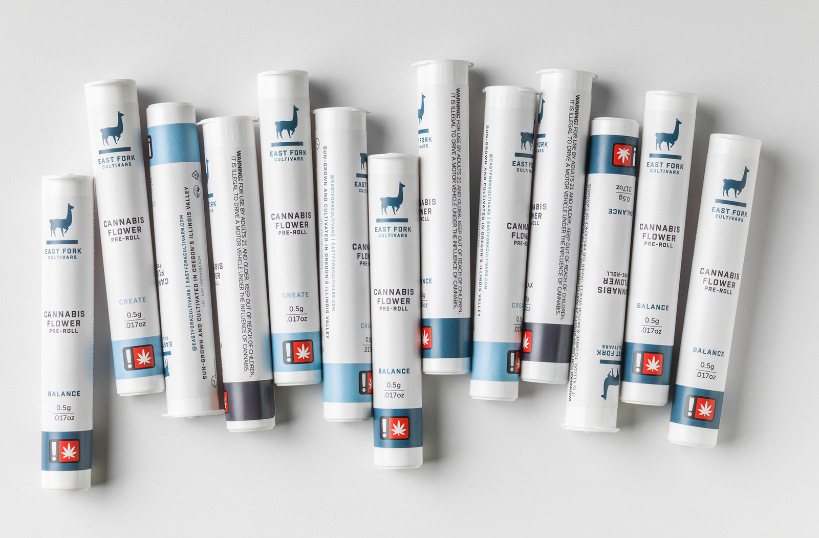 A row of white and blue East Fork Cannabis Flower branded pre-roll tubes, showing the East Fork llama logo, in Balance, Create, and Relax strains.